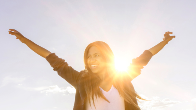 Person, die in der Sonne steht und lacht