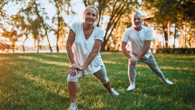 Sport im Freien Blogcover Zwei Personen, die auf einer Wiese Dehnübungen machen