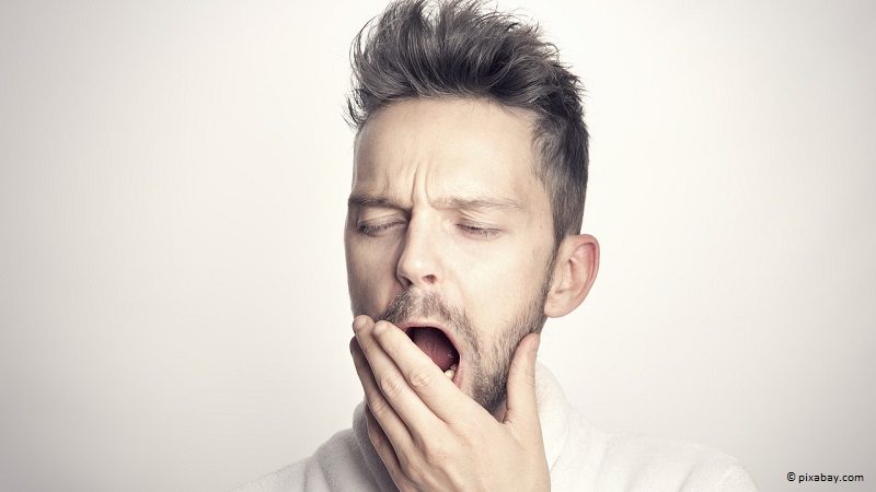 Erschöpfter, gähnender Mann, dem L-Arginin helfen würde.