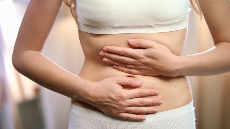 Leberentgiftung mit Mariendistel und Artischocken. Zu finden in unseren Artischocke und Mariendistel Kapseln von ApoLife. Junge Frau mit Schmerzen, der eine Leberentgiftung helfen würde.